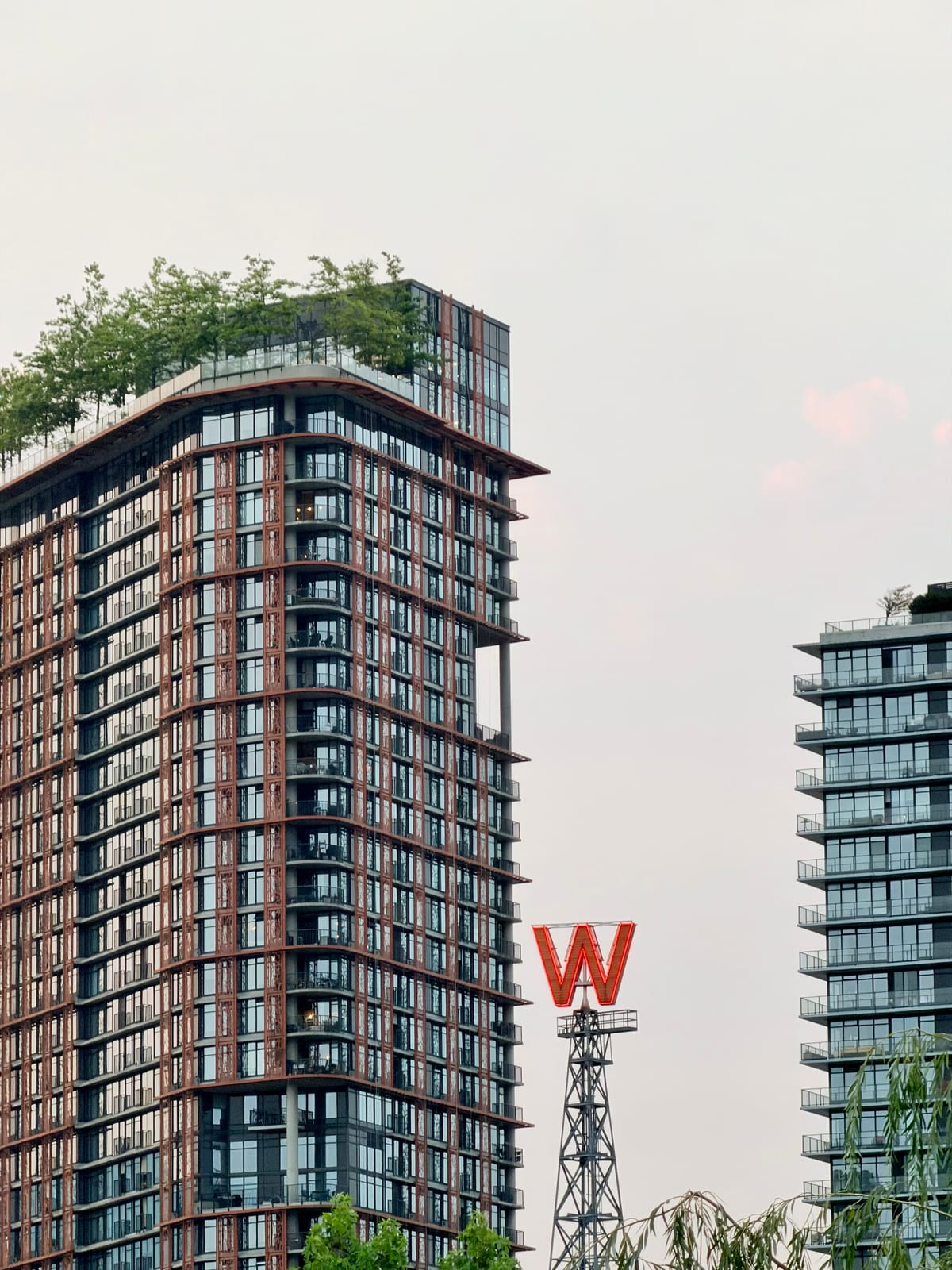 A red neon W sign framed by modern Vancouver apartment buildings