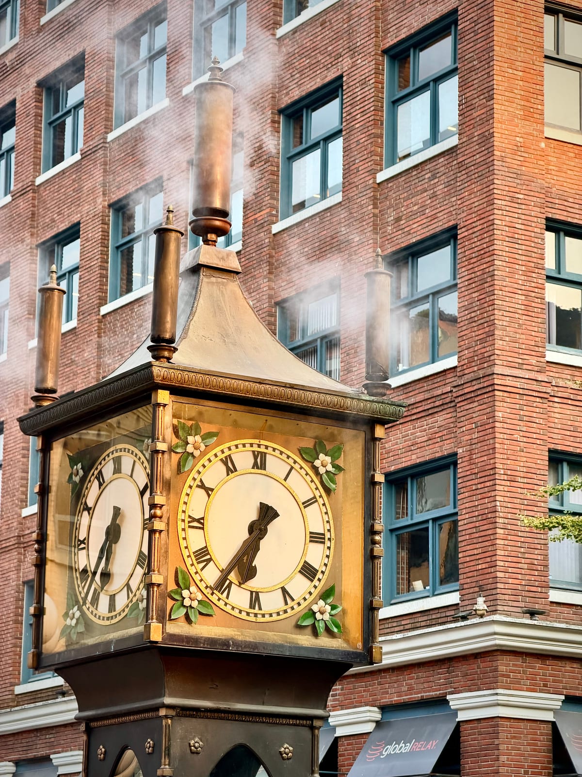Steam rising from the ornate Gastown steam clock in front of a brick building