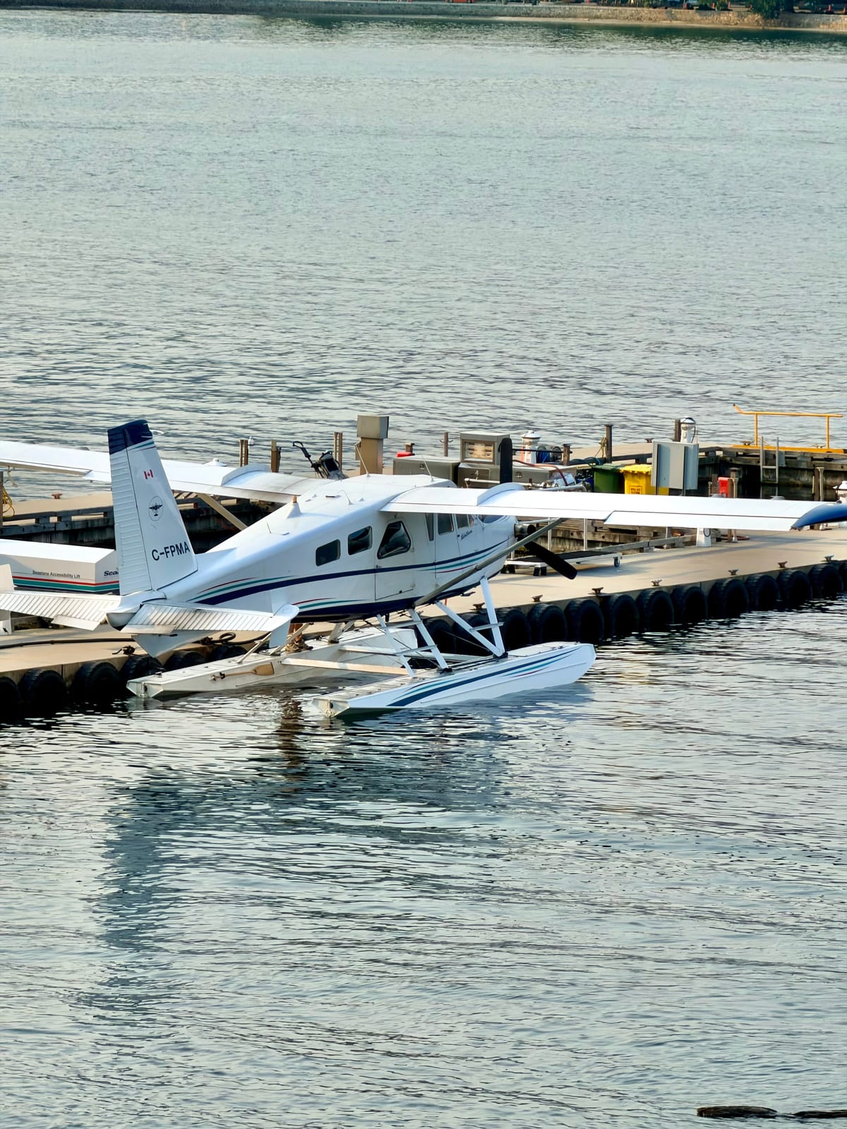A white seaplane docked on the water in Vancouver Harbour